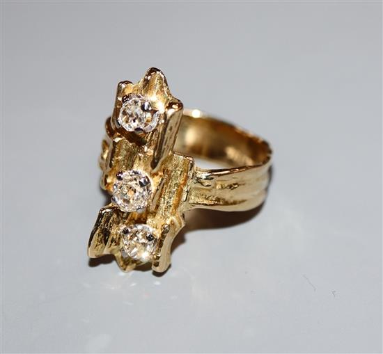 A 1970s? textured 18ct and three stone diamond set upfinger ring, size P.